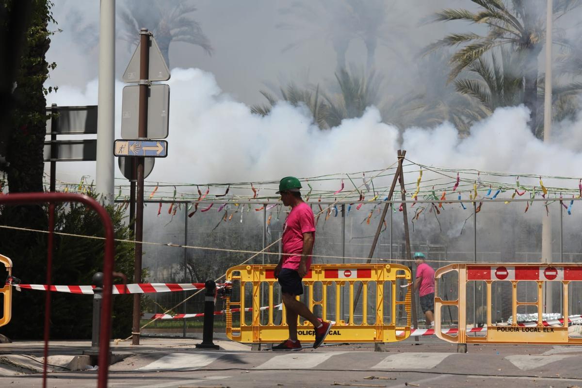 Un pirotecnico, durante el lanzamiento de hoy en Elche, con las palmeras cubiertas de humo