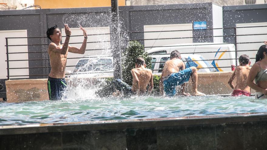 Jóvenes bañándose hoy al mediodía en una fuente de Orihuela