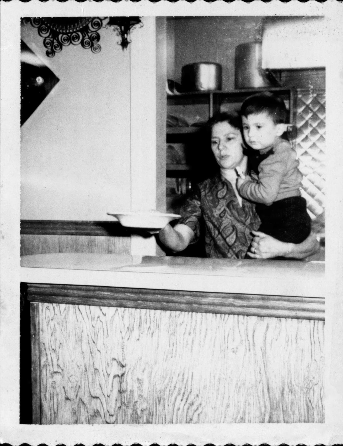 La madre de Pepe, Pilar Montero, cuida de su hijo pequeño llamado Frank mientras sirve comida en la taberna.