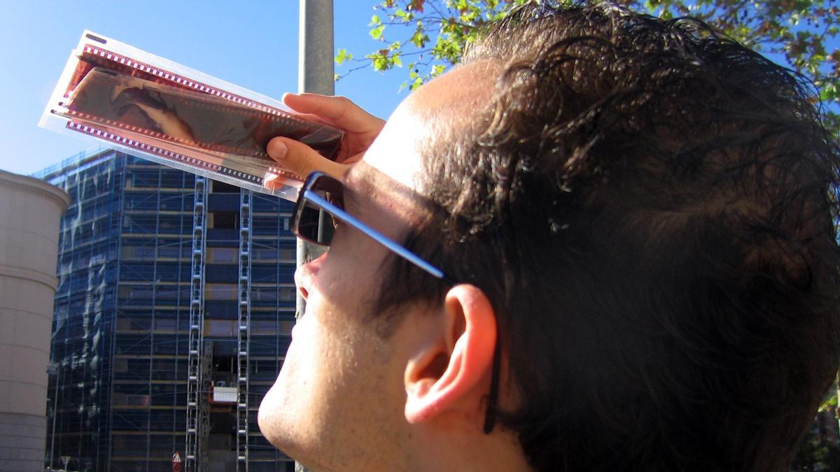 Un hombre mira un eclipse de Sol a través de unos negativos fotográficos.