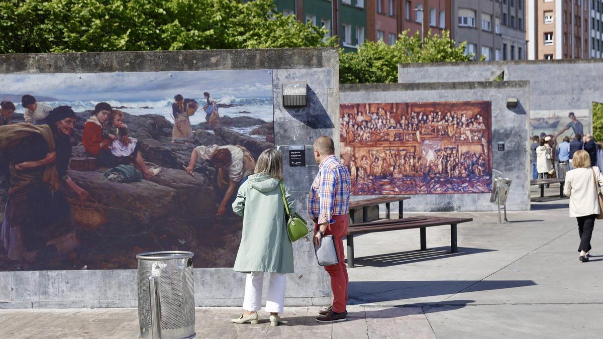 Dos personas contemplan una de las reproducciones pictóricas que se exhiben en el Paseo de Poniente.