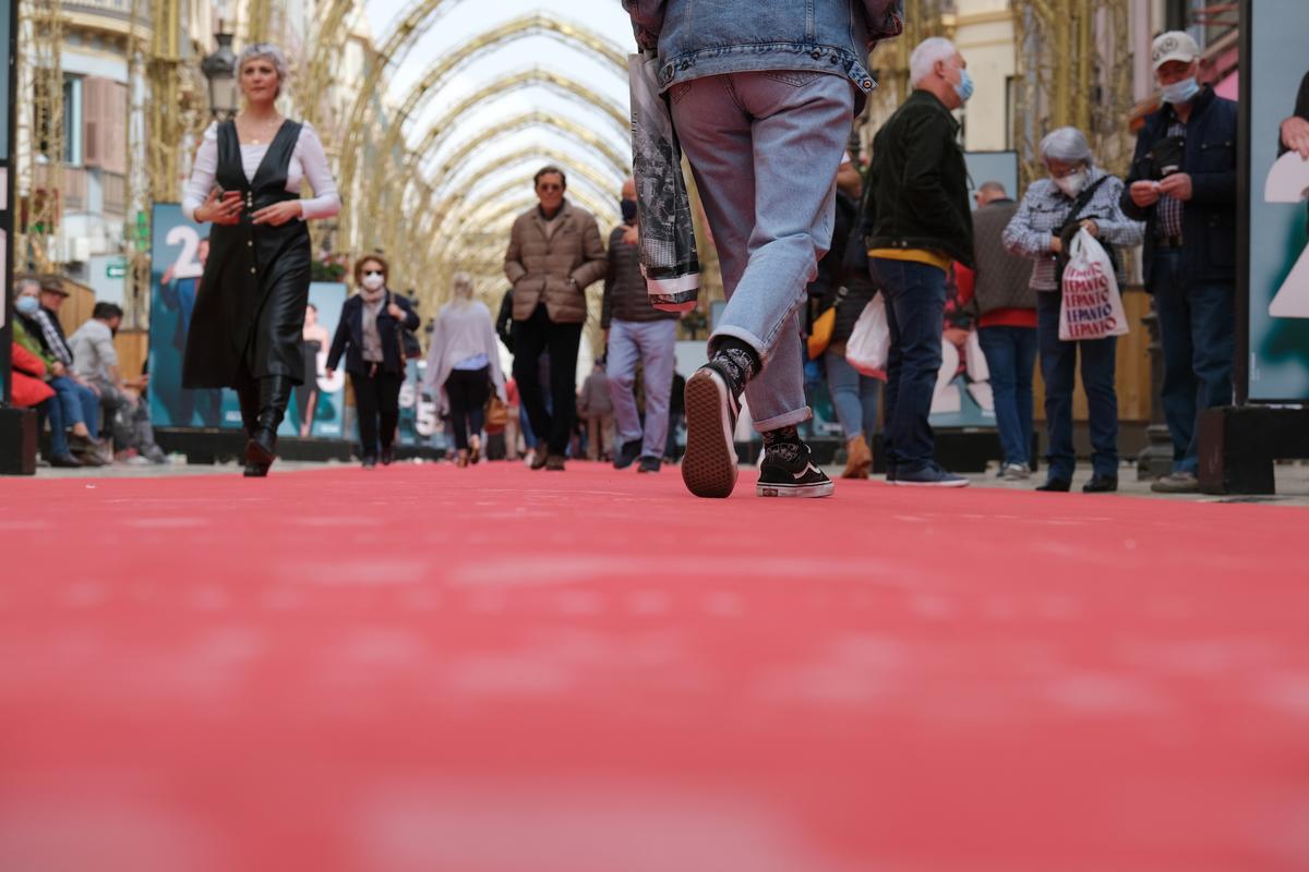 Abajo, la alfombra roja sobre la calle Larios. Arriba, los arcos de la iluminación navideña.