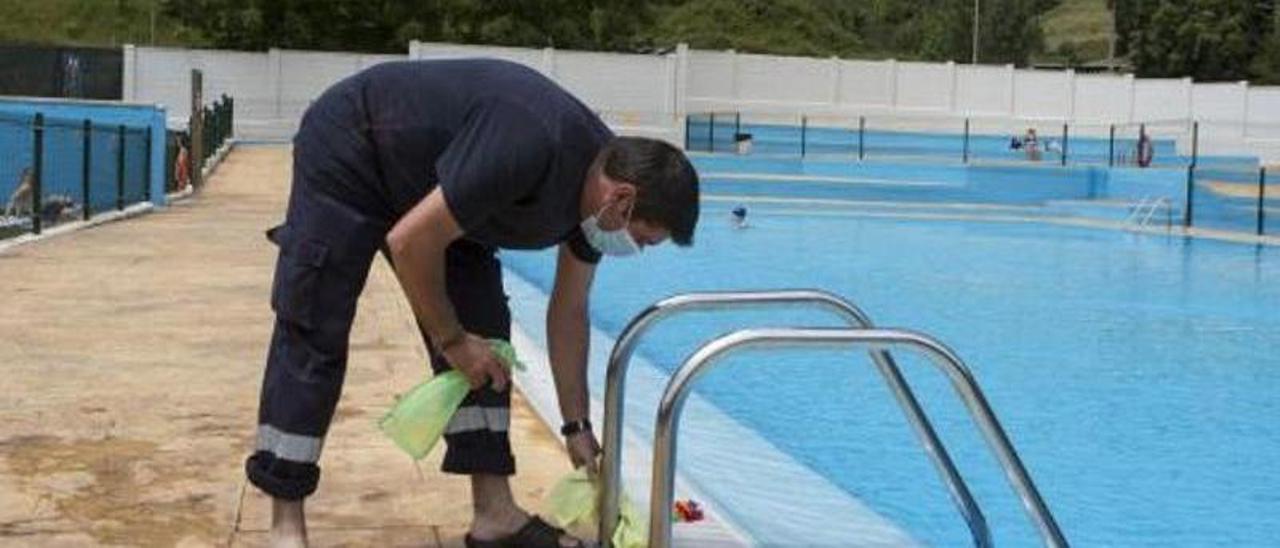 Un operario limpia la escalera de acceso a uno de los vasos de las piscinas de Riaño. | Fernando Rodríguez
