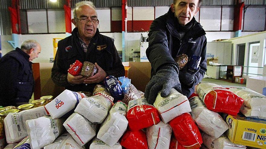 Dos voluntarios organizan diferentes productos en el almacén.