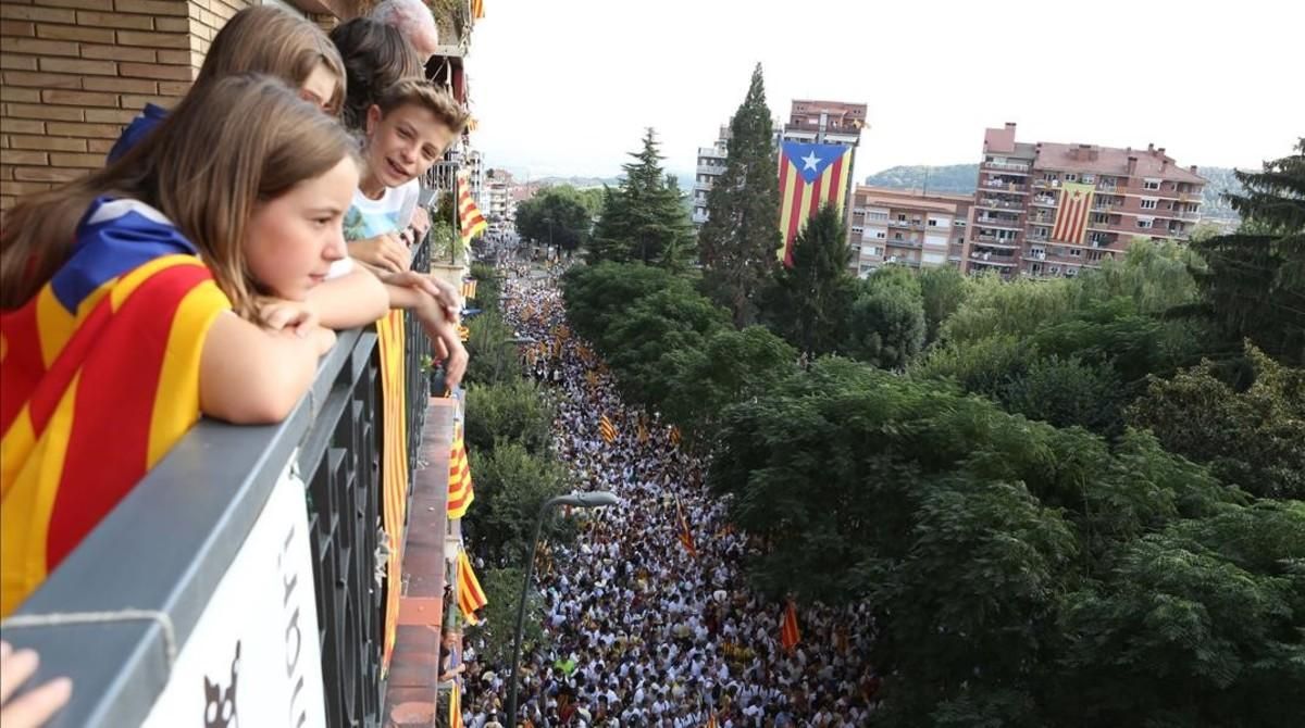 Unos vecinos siguen la manifestación desdel el balcón de un piso, en Berga.