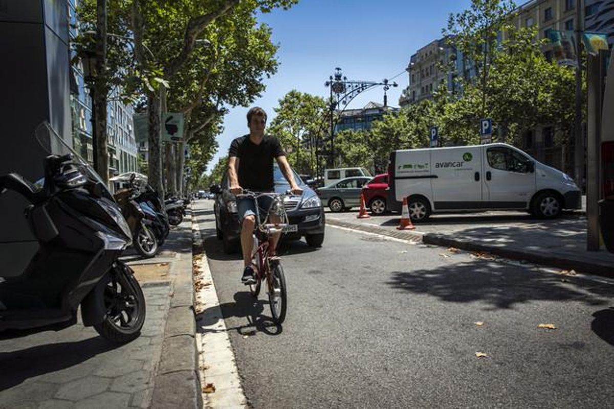 Un ciclista puja pel lateral de passeig de Gràcia enganxat a la vorera per permetre el pas dels vehicles motoritzats, ahir a la tarda.