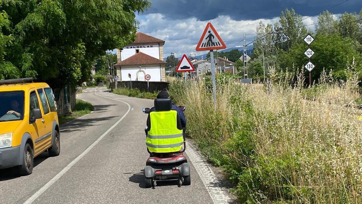 Una persona con movilidad reducida circula con su silla adaptada por la carretera de Caldelas de Tui.