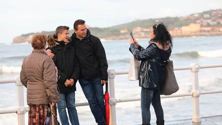 Turistas en Gijón, ayer, haciéndose una foto en el paseo de la playa de San Lorenzo.