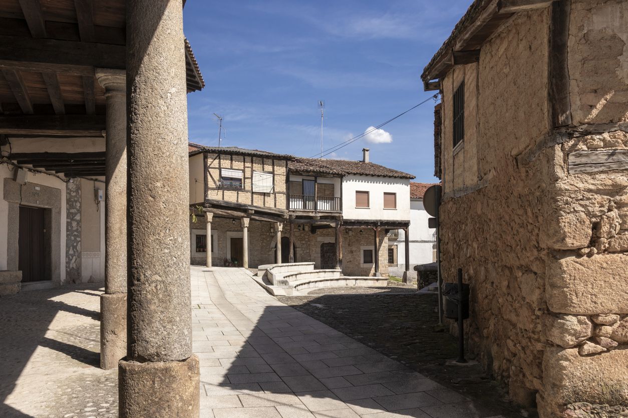 Plaza principal de Calatañazor que exhibe arquitectura tradicional y columnas de piedra en un día soleado.