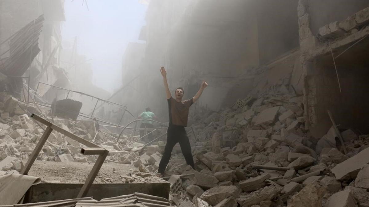 Un hombre pide ayuda en medio de los escombros de los edificios destruidos en una calle de Alepo.