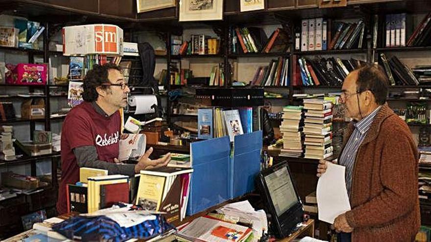 Miguel Ángel Viñas conversa con Luis González dentro de su librería.