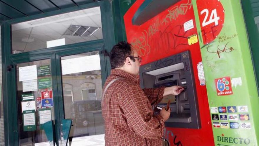 Un cliente saca dinero de un cajero en una sucursal financiera de Málaga.