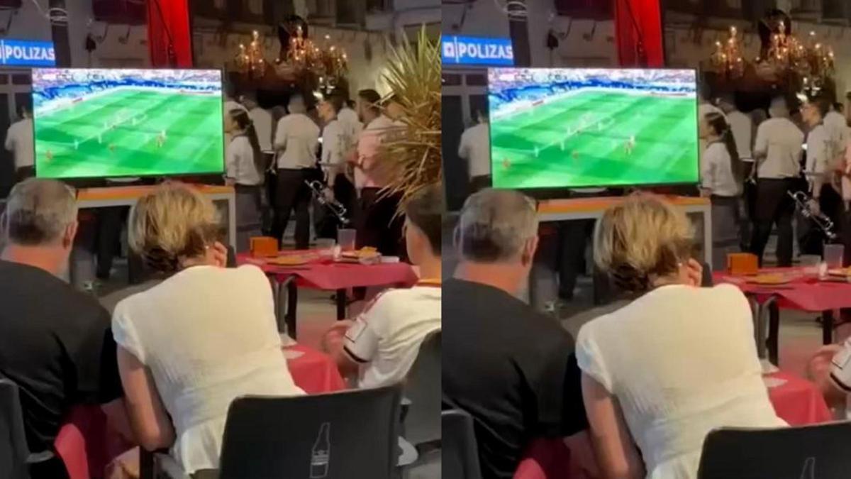Clientes del bar Cervería Birra Mía celebran el gol de Mike Merino mientras el paso de San benito procesiona por las calles de Lebrija.