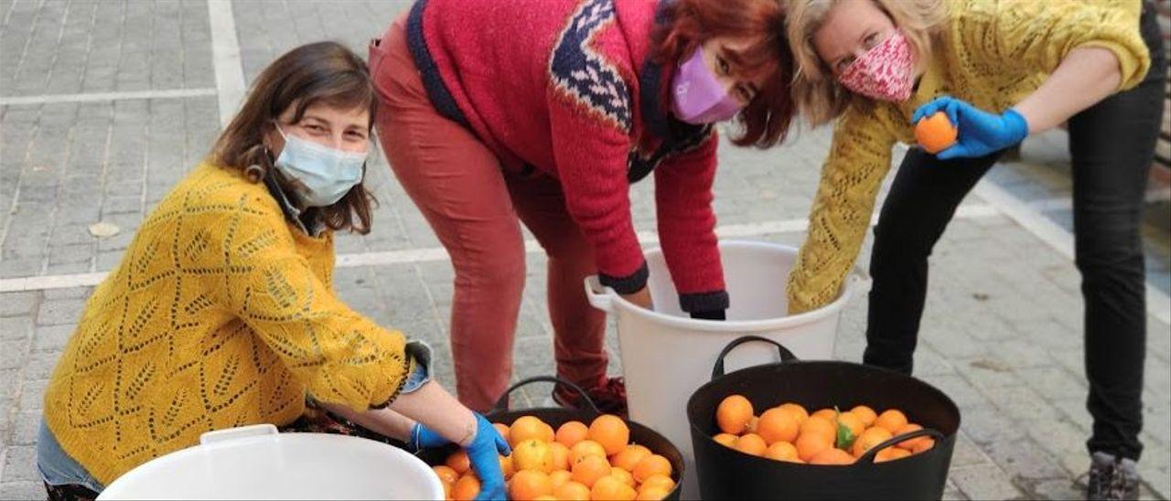 Vecinas recogiendo naranjas en la plaza del Banc de s&#039;Oli.