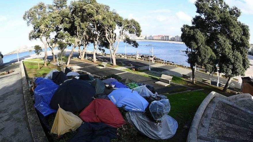 Paraguas y plásticos cubren el lugar en el que pernocta una mujer junto a la playa de Riazor.