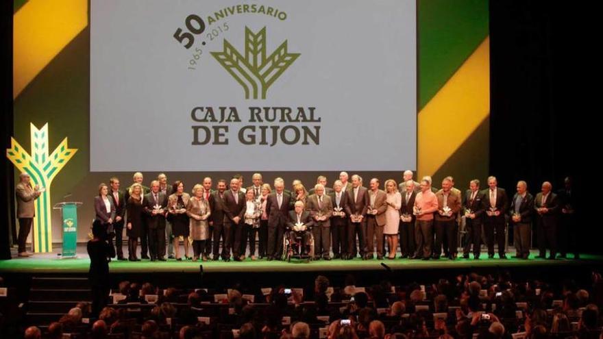 Los homenajeados, con la junta rectora de Caja Rural de Gijón sobre el escenario del teatro de la Laboral.