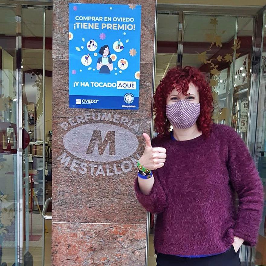 Raquel Iglesias, delante de su perfumería de la calle San Pedro Mestallón, con un cartel de la campaña. | LNE
