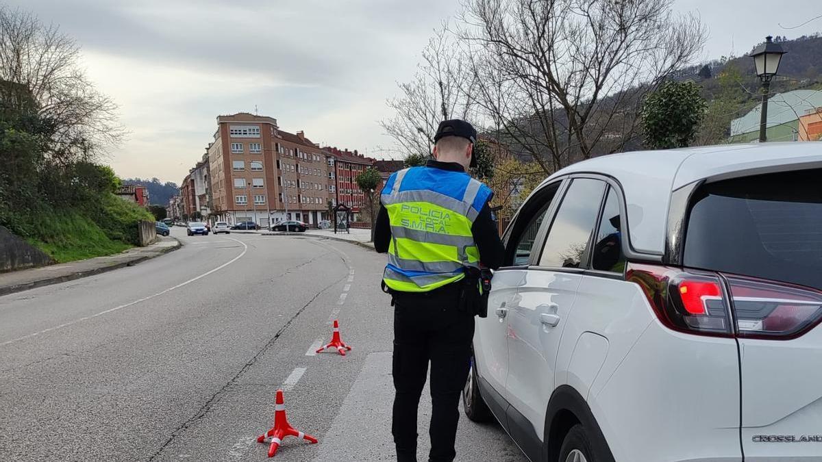 Un policía local, junto a un coche durante la campaña de control del cinturón de seguridad.