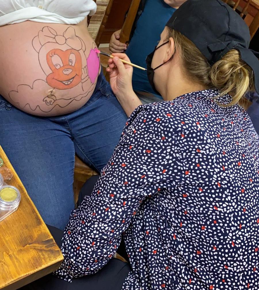 Cecilia Sanmartín pintando la barriga de una embarazada.