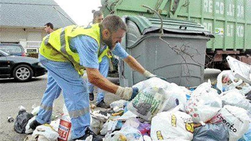 Un operario de Cespa procede a retirar bolsas acumuladas en la calle, ayer en Nigrán. / carlos pereira