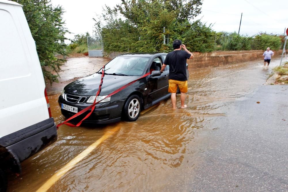 Varios vehículos circulan por un camino inundado por la intensa tormenta que ha caído esta mañana en el litoral norte de la provincia de Castelló que ha dejado algunas carreteras secundarias cortadas y ha provocado el rescate de seis vehículos en Benicarló, además de un pequeño accidente en Peñíscola y problemas por erosión en la playa del Clot de Vinaròs.