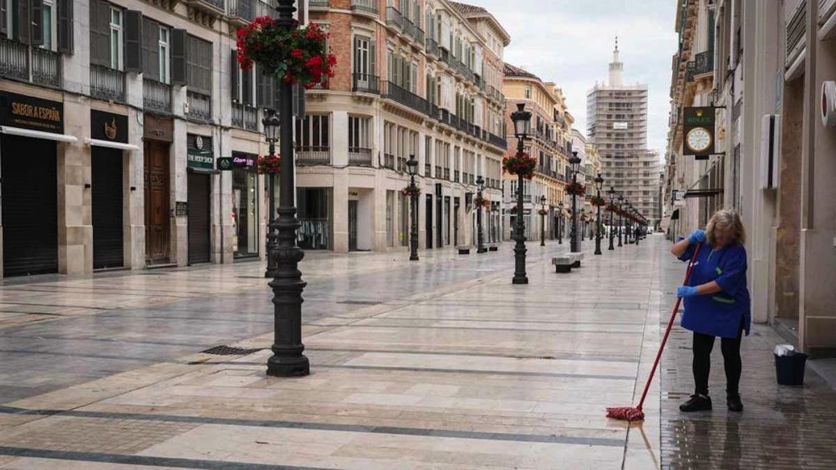 Una limpiadora friega la entrada de un portal en la calle Larios, este sábado.