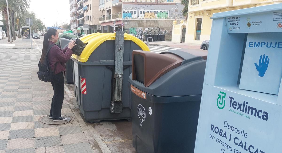 Una joven deposita la basura en el contenedor correspondiente.