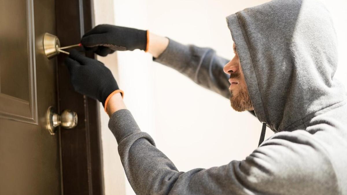 Persona intentando forzar la cerradura de una vivienda