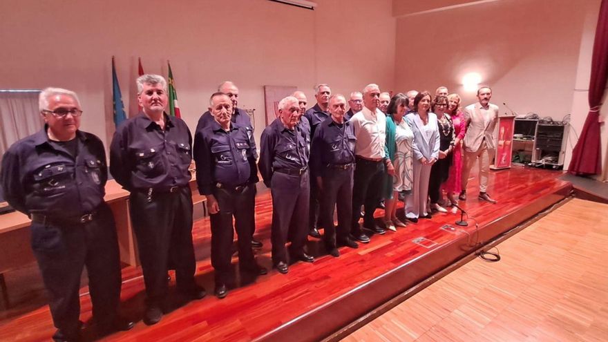 Los miembros del Coro Minero de Turón, a la izquierda, posan con representantes de Andade Asturias y de la Sociedad de los Humanitarios en el salón de actos del IES Valle de Aller. | D. M.