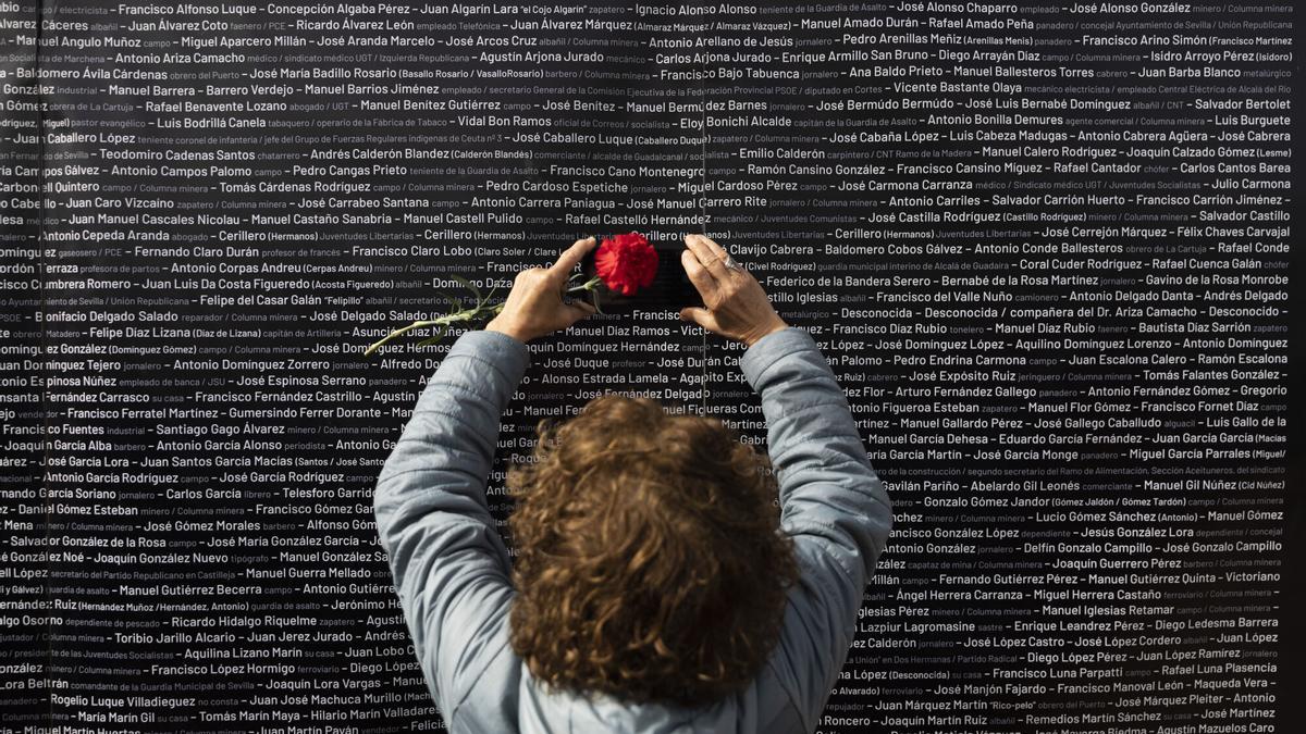 Una mujer hace una foto del nombre de su familiar, colocado en un panel junto a los nombres de las demás víctimas, durante el acto "institucional" de cierre de la fosa de Pico Reja, en el cementerio de San Fernando