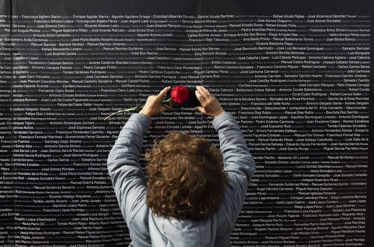 Una mujer hace una foto del nombre de su familiar, colocado en un panel junto a los nombres de las demás víctimas, durante el acto "institucional" de cierre de la fosa de Pico Reja. A 21 de febrero de 2023, en Sevilla (Andalucía, España). El Ayuntamiento de Sevilla ha organizado un acto "institucional" este martes 21 de febrero con el que cerrar la fosa de Pico Reja, en el cementerio de San Fernando, tras concluir los trabajos de exhumación realizados desde enero de 2020 por Aranzadi Sociedad de Ciencias por encargo del Consistorio hispalense y tras haber sido recuperados los restos óseos de 1.786 personas "asesinadas". 21 FEBRERO 2023 María José López / Europa Press 21/02/2023. María José López;category_code_new