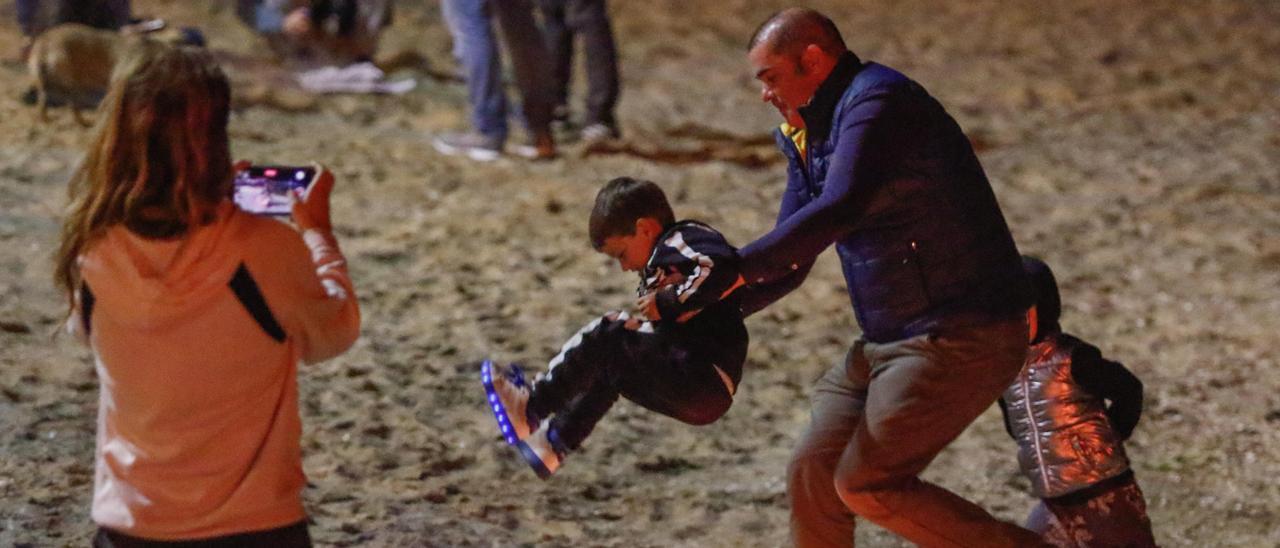 Un hombre ayuda a un niño a saltar la &quot;cachada&quot; en una playa de Vilagarcía