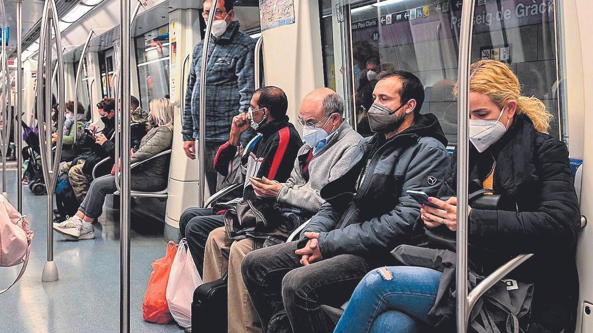 Viajeros con mascarilla en el metro.