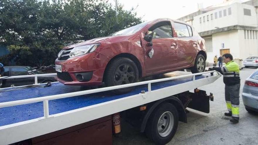 Una grúa se lleva el coche volcado en la calle San Jaime.