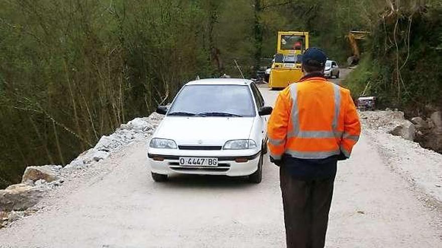 Un operario, ayer, frente a un coche, en la carretera de Llonín.