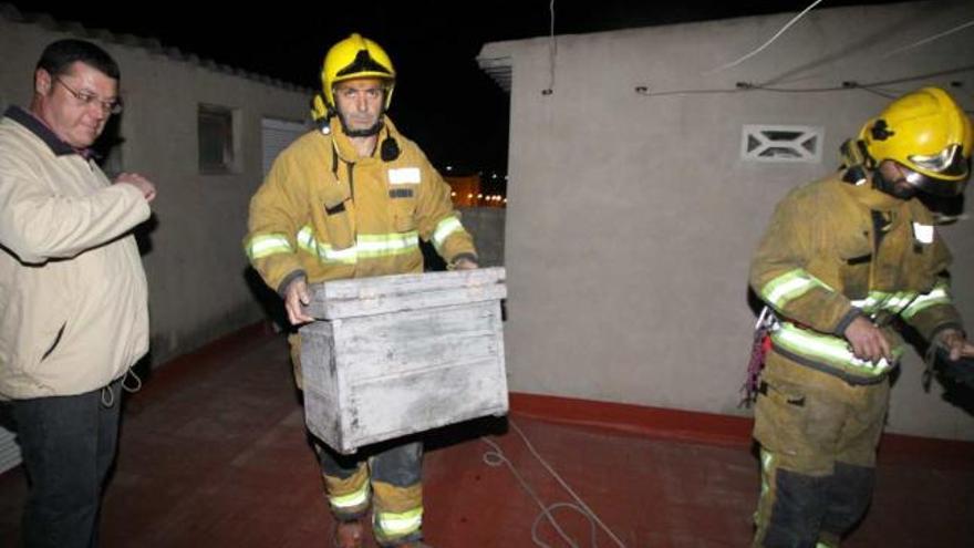 El propietario del piso y los bomberos anoche en la azotea retirando la caja con las abejas.