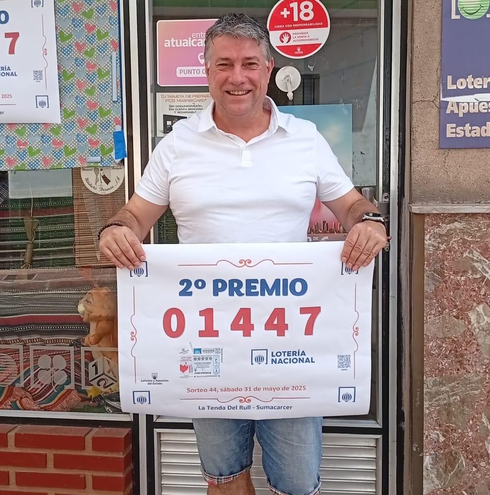 Pepe Sancho posa con el cartel que anuncia que ha repartido el segundo premio del sorteo del sábado.