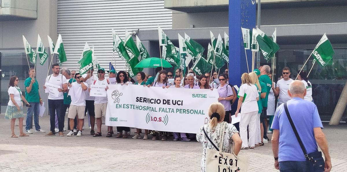 Dos personas pasan frente a la protesta, este viernes en el hospital de Gandia.