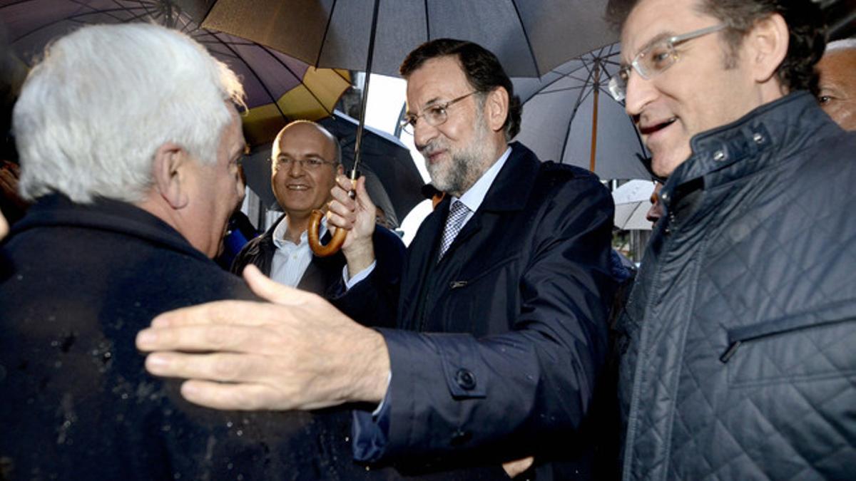 El presidente del PP y candidato a la presidencia del Gobierno, Mariano Rajoy, conversa con un hombre acompañado por el presidente de la Xunta de Galicia, Alberto Núñez Feijóo y por el presidente provincial del partido, Manuel Baltar.