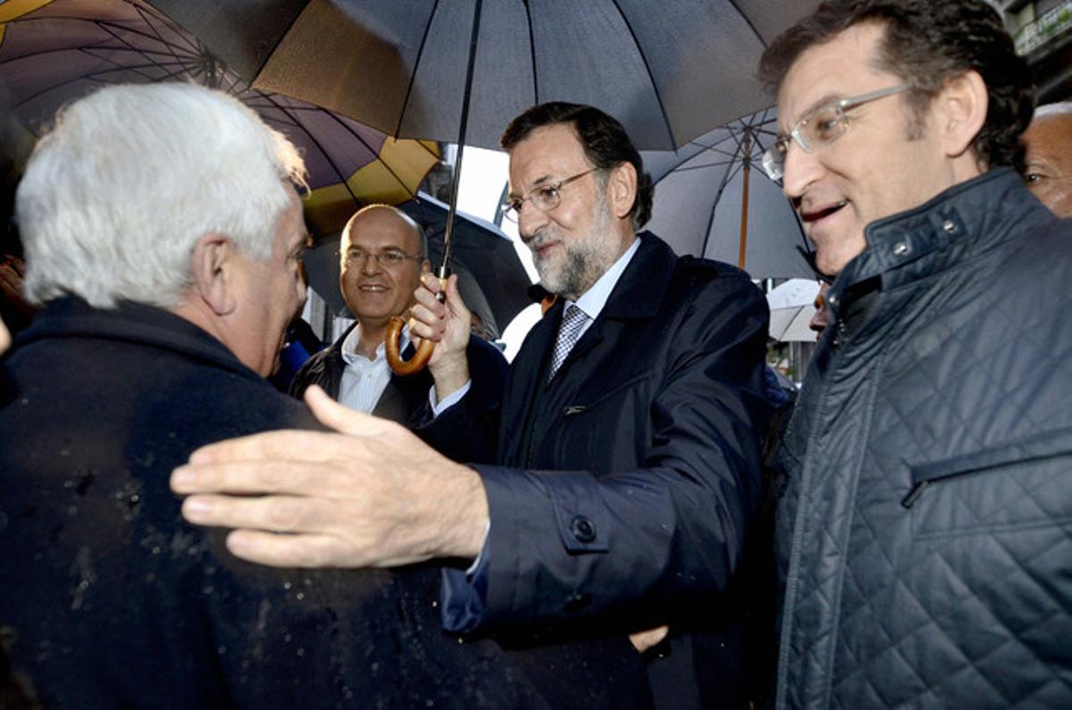 El presidente del PP y candidato a la presidencia del Gobierno, Mariano Rajoy, conversa con un hombre acompañado por el presidente de la Xunta de Galicia, Alberto Núñez Feijóo y por el presidente provincial del partido, Manuel Baltar.