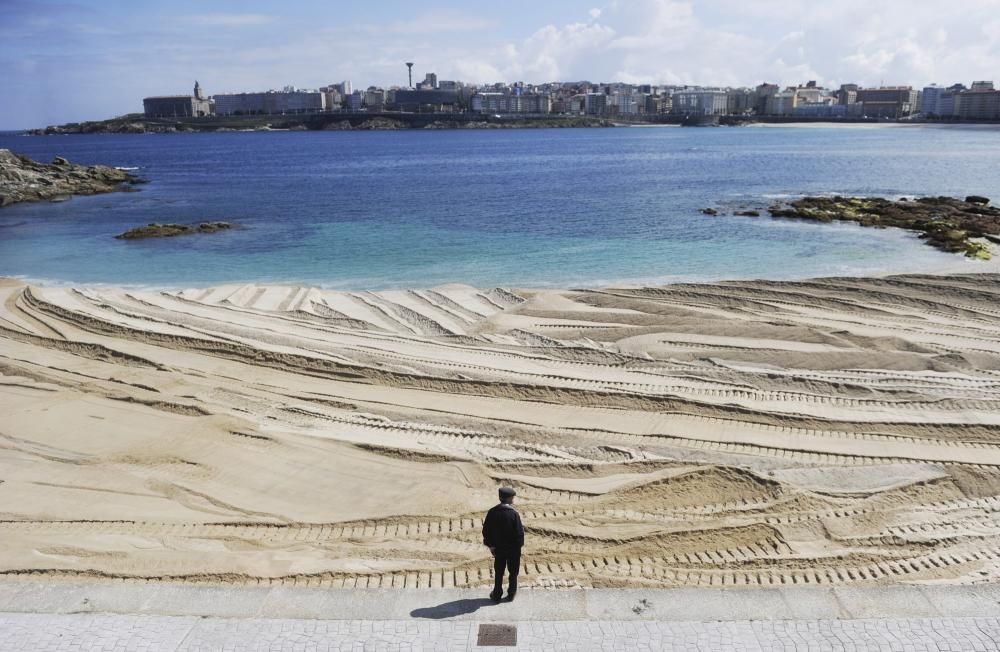 Las máquinas extienden la arena en la playa de Riazor.