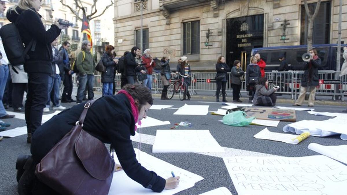 Varios manifestantes colocan en el suelo carteles contra los CIE, este viernes en Barcelona, ante la delegación del Gobierno en Catalunya.