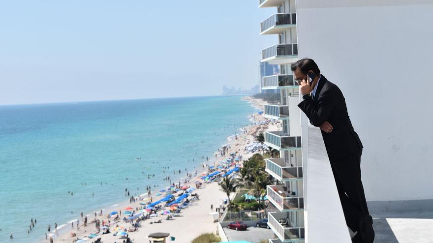 Un ejecutivo, al teléfono desde una terraza con vistas a la playa.