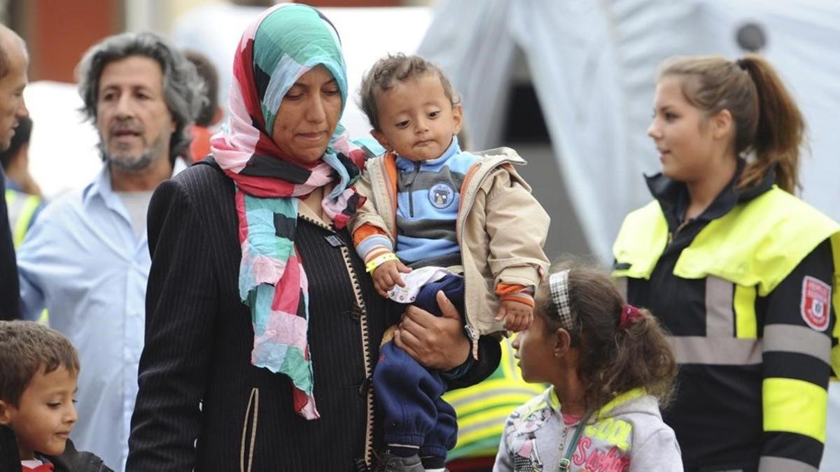 Una mujer y un niño, junto con otros migrantes y refugiados, son trasladados a un tren con destino a otra ciudad alemana poco después de su llegada a Múnich.