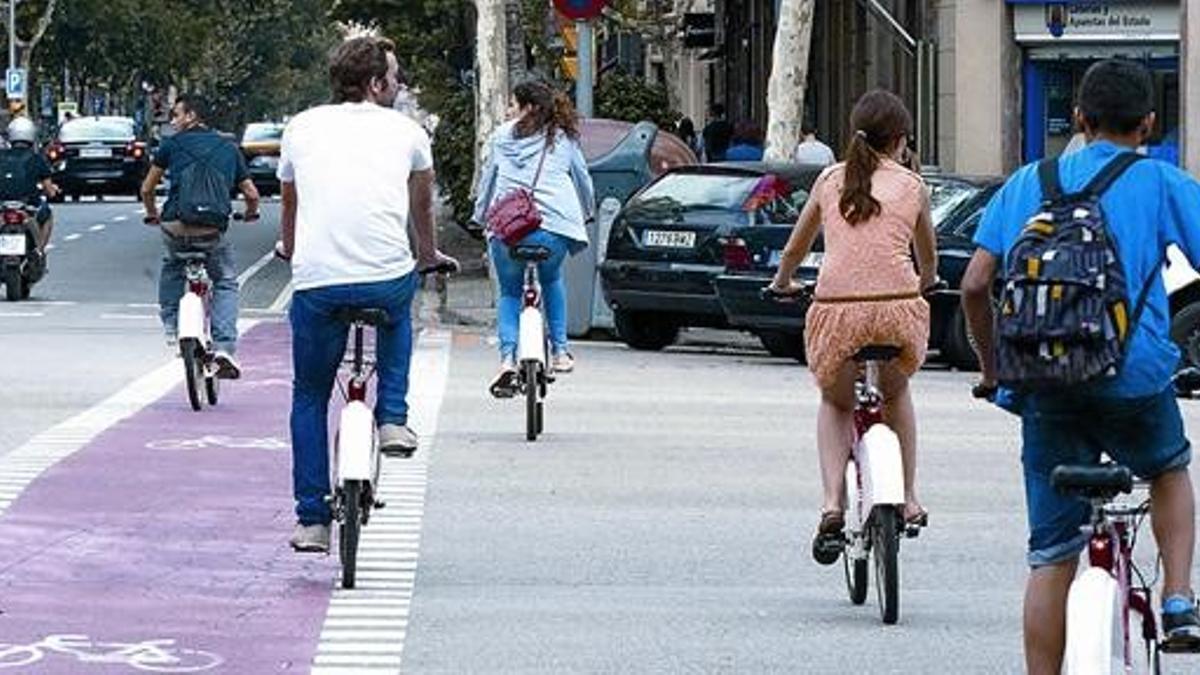 Usuarios del Bicing circulan por la calle del Consell de Cent.