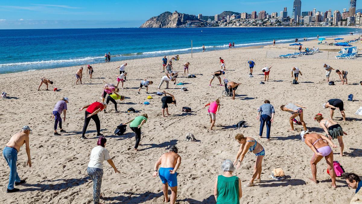 Personas mayores hacen gimnasia en la playa de Benidorm.