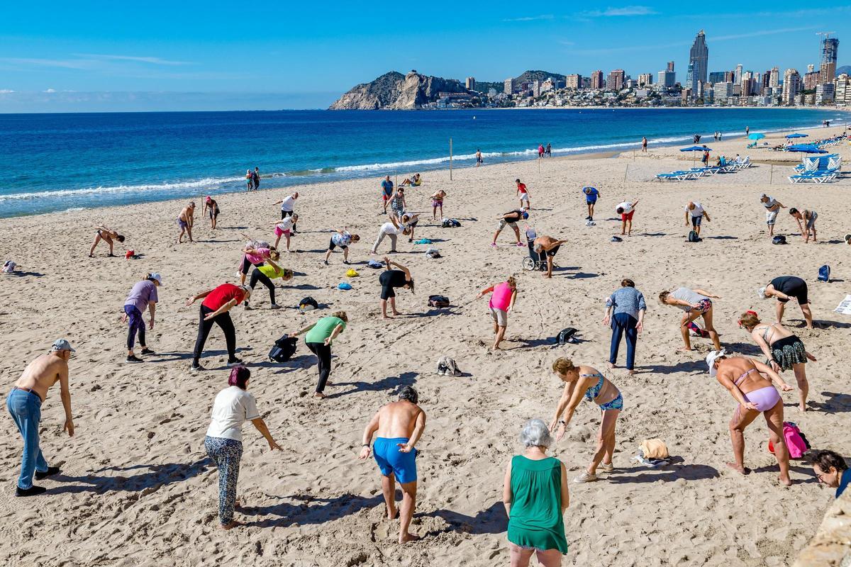 Personas mayores hacen gimnasia en la playa de Benidorm.