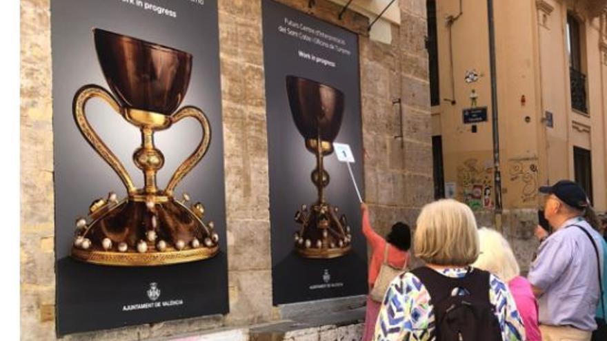 Los turistas atienden la explicación de la guia delante de las lona del Santo Cáliz de la Casa del Relojero