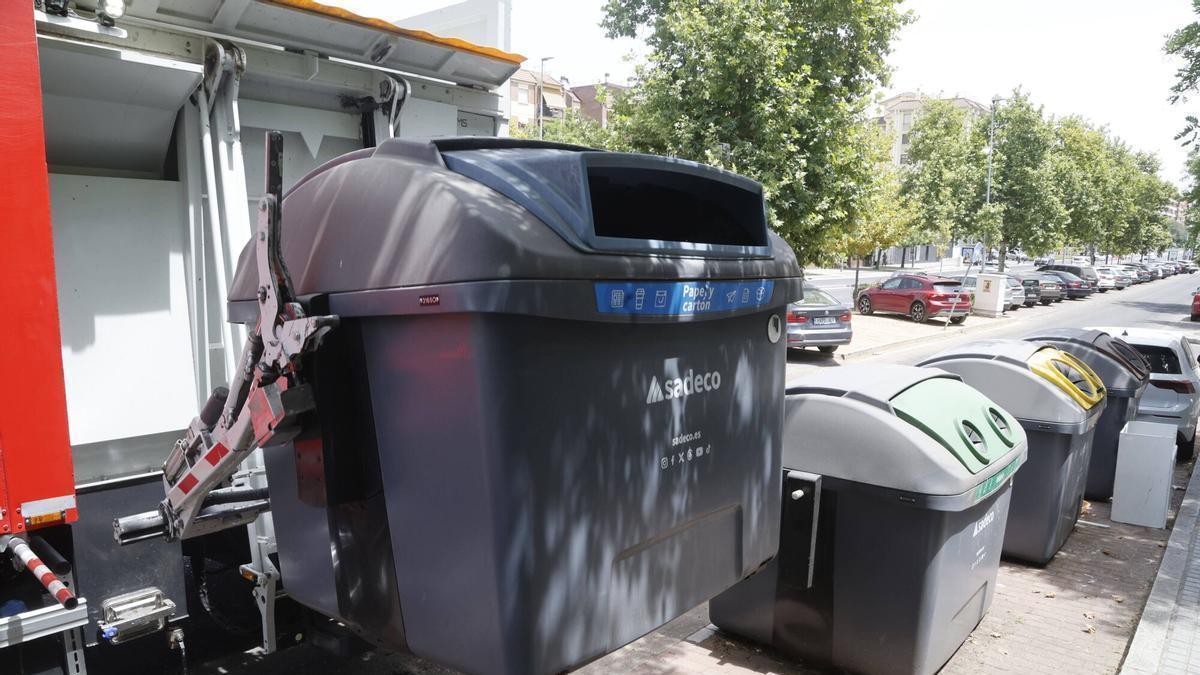 Un camión de Sadeco eleva un contenedor de papel y cartón.