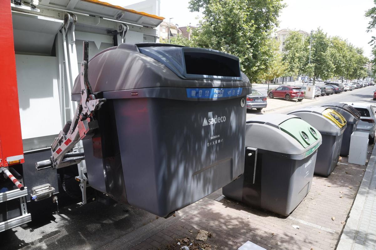 Un camión de Sadeco eleva un contenedor de papel y cartón.